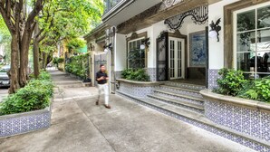 A building with a traditional facade, steps leading to a door, and a tree-lined sidewalk. - Casa Talavera by Tasman (Mexico City)