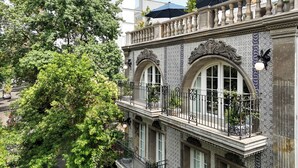 A building with ornate tiled facades, arched windows, and a balcony with a wrought iron railing. - Casa Talavera by Tasman (Mexico City)