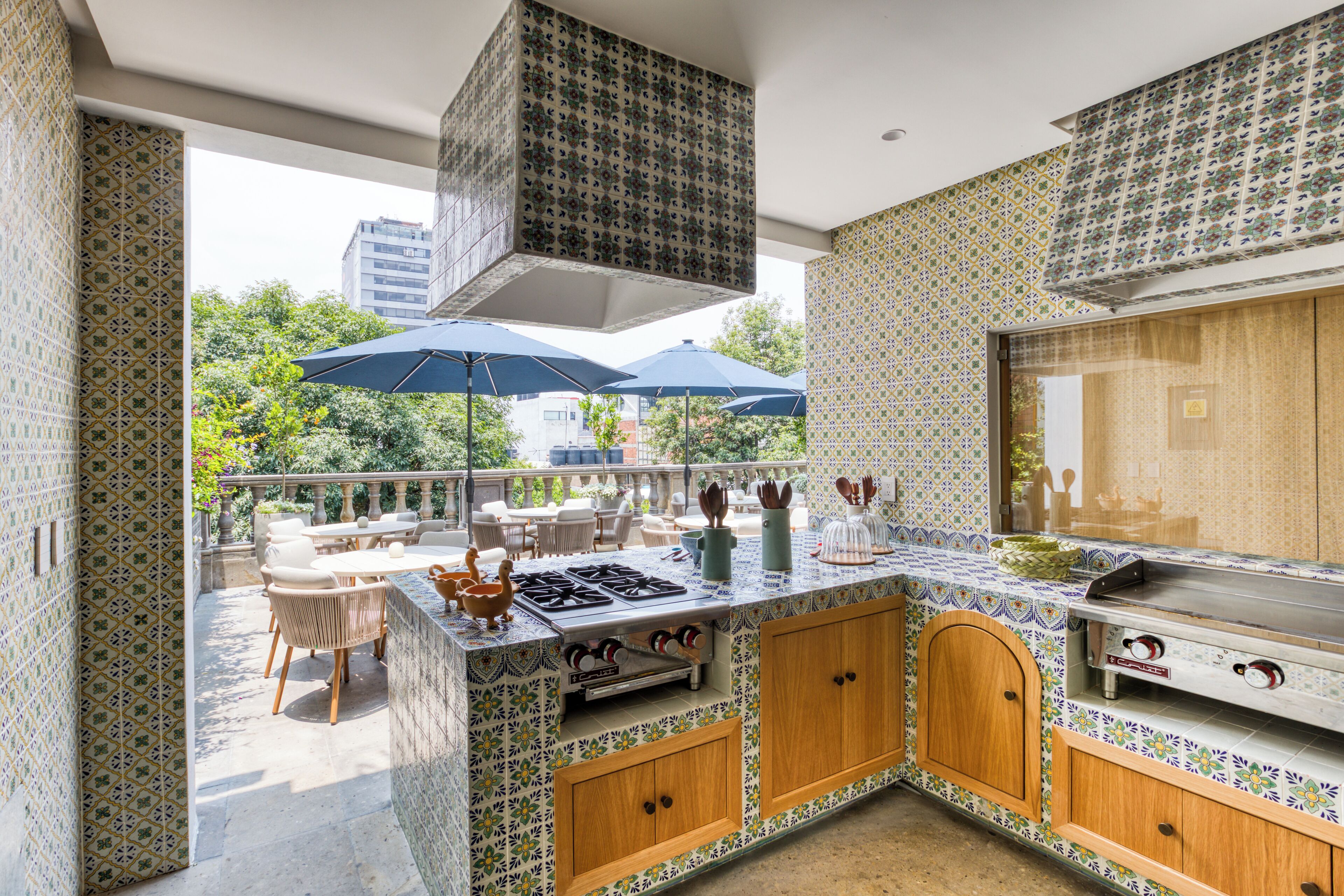 A kitchen with a tiled backsplash, wooden cabinets, a gas stove, and a dining area with outdoor seating.