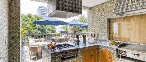 A kitchen with a tiled backsplash, wooden cabinets, a gas stove, and a dining area with outdoor seating.