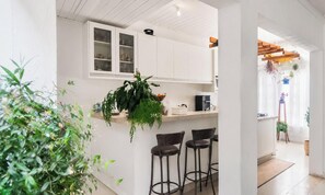 Une cuisine moderne avec des meubles blancs, une machine à café et des tabourets de bar.