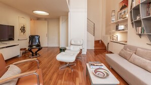 Un salon moderne comprenant un canapé, une table basse, un téléviseur et une bibliothèque.