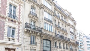 Un immeuble à plusieurs étages, de style architectural classique, caractérisé par des balcons richement décorés et de grandes fenêtres.