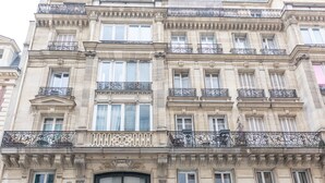 Un immeuble à plusieurs étages, doté de balcons décoratifs, de grandes fenêtres et d’une enseigne bien visible.