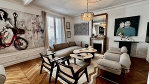 Ein Wohnzimmer mit einer Couch, Sesseln, einem Kamin und Kunstwerken an den Wänden.