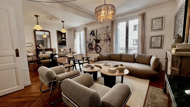 Ein geräumiges Wohnzimmer mit einer großen Couch, Sesseln, einem Couchtisch und einem Essbereich mit Stühlen und einem Tisch.