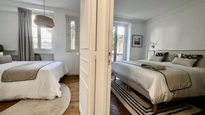 Ein Schlafzimmer mit zwei Betten, einem Fenster, einer Tür und Blick ins Freie.