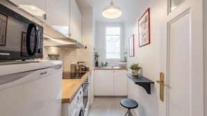 Une cuisine compacte équipée d’un lave-linge, d’un four à micro-ondes et d’un évier.