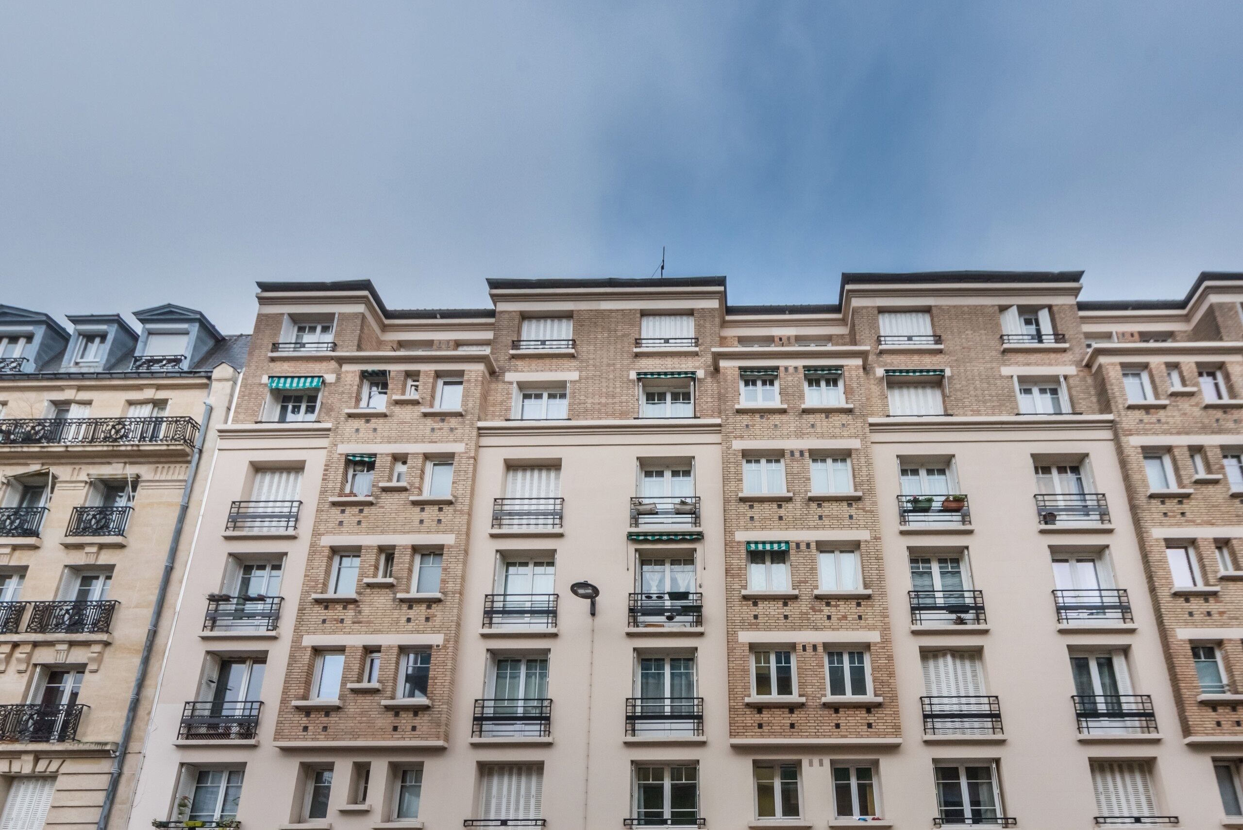 Un edifici d'apartaments de diversos pisos amb balcons, teulada plana i façana uniforme.