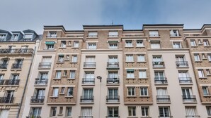 Un immeuble résidentiel à plusieurs étages, doté de balcons, d’un toit plat et d’une façade uniforme.