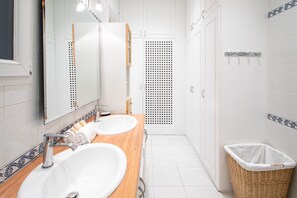 A bathroom with two sinks, a mirror, a shower, and a trash bin. - Grands Boulevards Family (Paris)