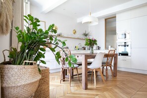 Eine moderne Küche mit einem Holztisch, weißen Stühlen und einer hängenden Pflanze.