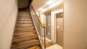 Una escala de fusta amb barana metàl·lica que porta a una porta amb un rètol a dalt.
