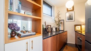Una cuina moderna amb armaris de fusta, taulell negre i forn de mur.