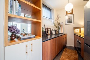 A modern kitchen with wooden cabinets, a black countertop, and a built-in oven. - Marais Enfants Rouges (Paris)