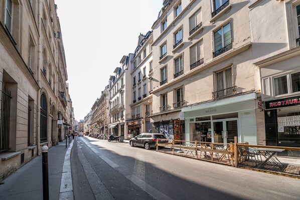 A street with buildings, a parked car, and a sidewalk. - Opera Home - Two Bedroom Apartment, Sleeps 4 (Paris)