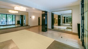 A spacious lobby with a large mirror, a chandelier, and a glass wall. - Buttes Chaumont Botzaris View (Paris)