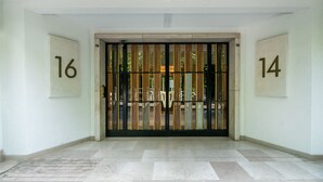 A gated entrance with numbers 14 and 16 on the walls, a tiled floor, and a view through the gate. - Buttes Chaumont Botzaris View (Paris)