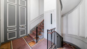 A staircase with wooden steps and a black railing, leading to a landing with a door. - Palais Royal Design - One Bedroom Apartment, Sleeps 5 (Paris)