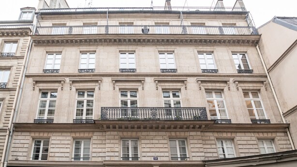 A multi-story building with a classical architectural style, featuring a balcony with ornate metal railings and a sign reading 'SCOOT-OPERA' on the ground floor. - Palais Royal Design - One Bedroom Apartment, Sleeps 5 (Paris)