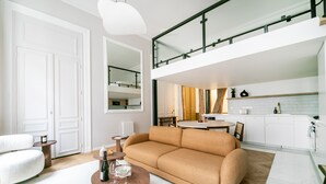 A modern living room with a sofa, a coffee table, and a dining area with a table and chairs. - Palais Royal Design - One Bedroom Apartment, Sleeps 5 (Paris)