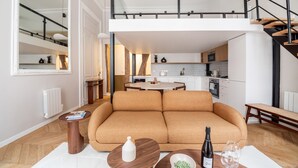 A modern apartment with a living room, kitchen, and a staircase leading to an upper floor. - Palais Royal Design - One Bedroom Apartment, Sleeps 5 (Paris)