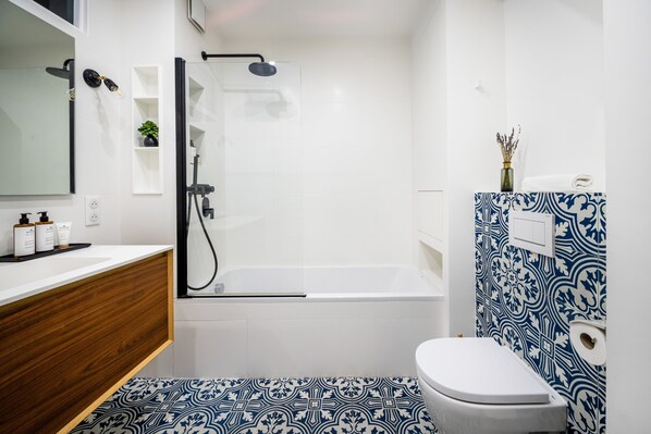 Uma casa de banho moderna com chuveiro, sanita e toucador.