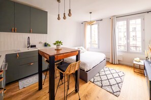 A modern bedroom with a bed, bedside table, and a window with curtains. - Belleville Studio - Studio Apartment, Sleeps 2 (Paris)