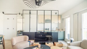 A modern living room with a sofa, a coffee table, a TV, and a kitchen in the background. - Tour Eiffel Grenelle (Paris)