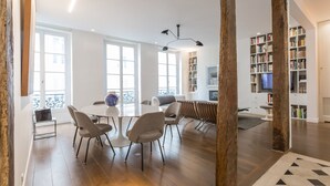 A spacious living area with a round table, chairs, a bookshelf, and a television. - Île Saint Louis Luxury (Paris)
