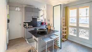 Eine kompakte Küche mit modernen Geräten, ein Essbereich mit Barhocker und Blick durch ein großes Fenster.