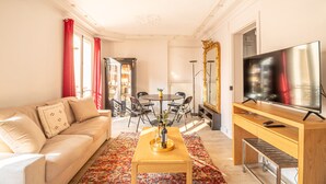 Ein Wohnzimmer mit Sofa, Couchtisch, Fernseher und Essbereich.
