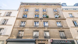 Ein mehrgeschossiges Gebäude mit aufwendigen architektonischen Details, darunter dekorative Gesimse und Balkone mit schmiedeeisernen Geländern.