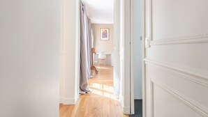 A hallway with a wooden floor, white walls, and a door on the right. - Marais Saint Paul - Two Bedroom Apartment, Sleeps 6 (Paris)