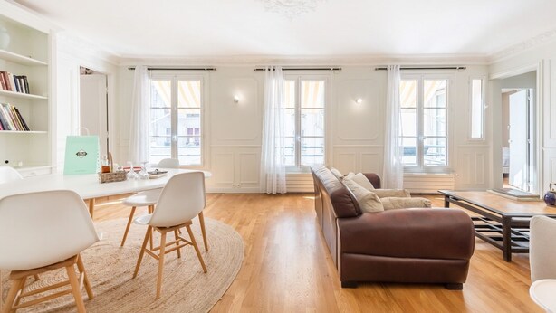 A spacious living room with a sofa, chairs, a coffee table, and a bookshelf. - Marais Saint Paul - Two Bedroom Apartment, Sleeps 6 (Paris)