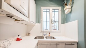 A kitchen with a window, stainless steel sink, and white cabinets. - Marais Saint Paul - Two Bedroom Apartment, Sleeps 6 (Paris)