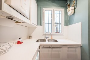 Eine Küche mit Fenster, Edelstahlspüle und weißen Schränken.