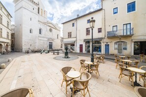 A courtyard with outdoor seating, a fountain, and historic buildings. - L’Escapade Nîmoise - grand studio centre Nîmes (Nimes)