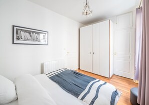 Ein Schlafzimmer mit Bett, einem gerahmten Bild an der Wand, einem Kleiderschrank und einer Tür.