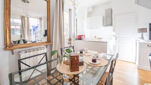 A dining area with a glass table, chairs, a wooden tea box, and a mirror on the wall. - Bon Marché Sevres - Two Bedroom Apartment, Sleeps 4 (Paris)