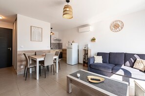 A modern living room with a sofa, coffee table, and dining area. - L'Alzeta - climatisé proche plage (Cervione)