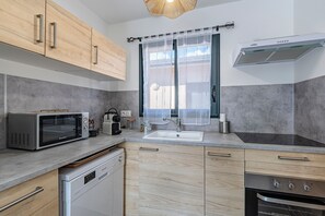A modern kitchen with a microwave, toaster, sink, dishwasher, and oven. - L'Alzeta - climatisé proche plage (Cervione)