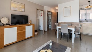 Una sala moderna con televisor, comedor y cocina.