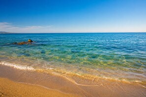 A beach with clear water, sandy shore, and distant land. - L'Alzeta - climatisé proche plage (Cervione)