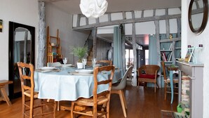 Un comedor con una mesa redonda, sillas de madera y una lámpara colgante.