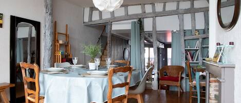 A dining area with a round table, wooden chairs, and a hanging light fixture.