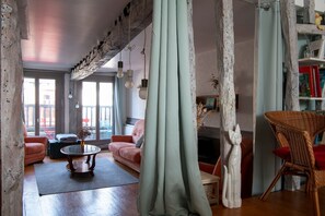A living room with a sofa, a coffee table, a wicker chair, and a fireplace. - La demeure du pêcheur - proche plage (Saint-Valery-sur-Somme)