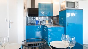 Eine kompakte Küche mit blauen Schränken, einer Mikrowelle und einem Spülbecken.