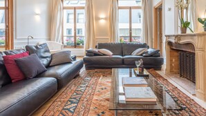 A living room with a sofa, a coffee table, and a fireplace. - Jardin du Luxembourg Home (Paris)