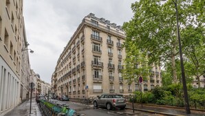 A street with parked cars, bicycles, and a building with multiple balconies. - Jardin du Luxembourg Home (Paris)